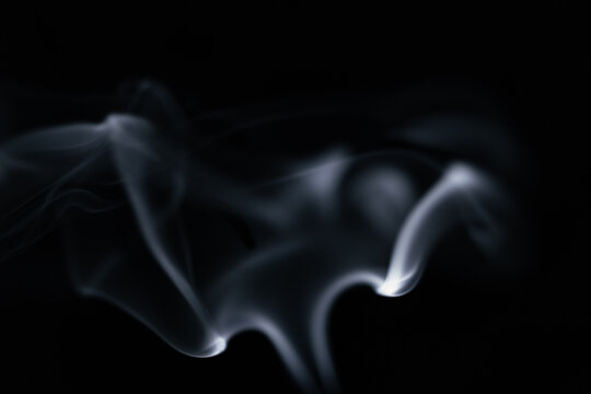 A graceful swirl of smooth white smoke against a dark background, forming a beautiful flowing shape