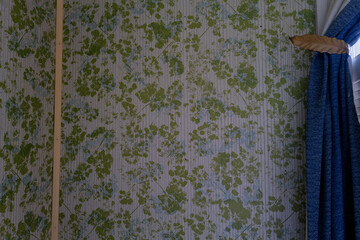 Blue curtain against old historic wallpaper in a abandoned home