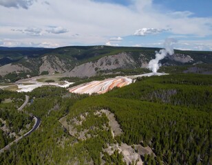 High-altitude view of geothermal area with mountains and forest