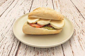 Delicious grilled chicken sandwich with fresh spinach, tomato, and avocado, on rye bread with basil pesto