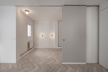 Empty boutique hotel room with lacquered white wardrobes, brushed aluminum accent doors, and a full-length mirror