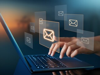 Hands using laptop with digital email icons floating in a futuristic interface communication