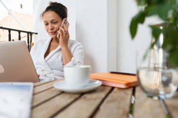 Woman Working Remotely While Talking on Phone and Using a Laptop