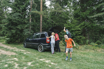 Fototapeta premium Family preparing for hike in the woodlands. Father and son, mom and daughter. Family with child with disability enjoying outdoor adventure in nature.