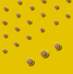 Chocolate truffle candies arranged in diagonal rows on vibrant yellow background
