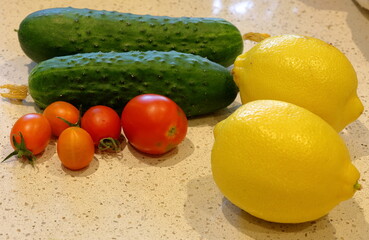 Mix of vegetables at table. Lemons, tomatoes and cucumbers. Vegetarian day.