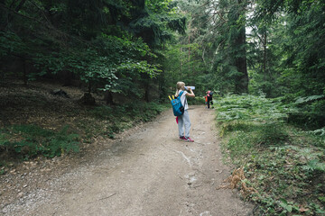 Obraz premium Short break while hiking. A girl drinks water.