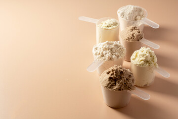 Protein powder in scoops. Different flavours of whey protein powder, copy space.