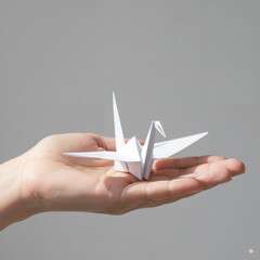 White origami crane held in a hand against a neutral background