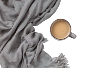A cozy scene of a light beige coffee mug resting on a dark background, draped with a gray textured blanket