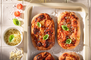 Homemade pinsa Margherita served with olive oil and basil.