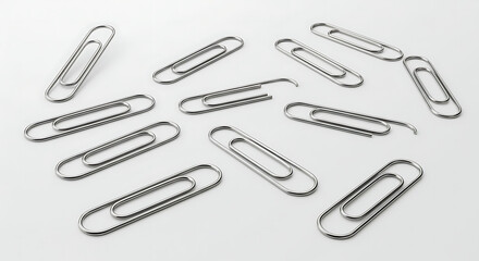 A Collection of Shiny Metal Paper Clips Scattered on a White Background Showcasing Office Stationary Essentials and Workplace Organization Accessories