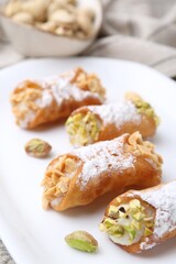 Delicious cannoli with ricotta cheese, peanuts, pistachios and powdered sugar on table, closeup