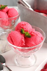 Delicious raspberry sorbet with mint in dessert bowls on white wooden table, closeup