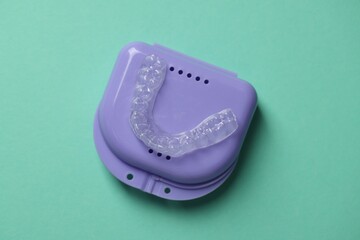 Clear aligner and retainer case on turquoise background, top view