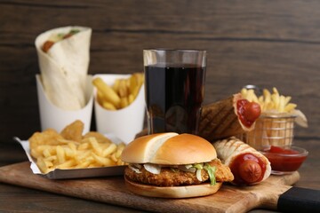 Different delicious fast food and cola on wooden table, closeup