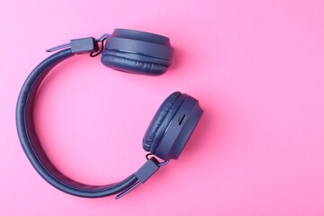 Pair of stylish blue headphones on pink background, top view. Space for text