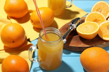 Freshly squeezed orange juice, fruits and juicer on blue wooden table, closeup