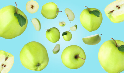 Fresh green apples swirling in air against light blue background