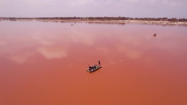 SENEGAL - 7.14.2025 - Amazing aerial footage circling all the way around a man rowing a boat on Dakar, Senegal's Pink Lake.