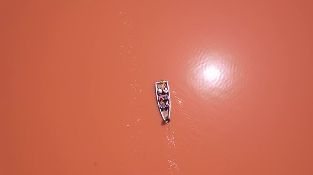 SENEGAL - 7.14.2025 - Very good overhead view of a man rowing a boat of tourists across Dakar, Senegal's Pink Lake.