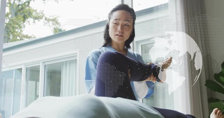 Therapist lifting leg rotating foot assessing range of motion in therapy with digital globe overlay - Powered by Adobe