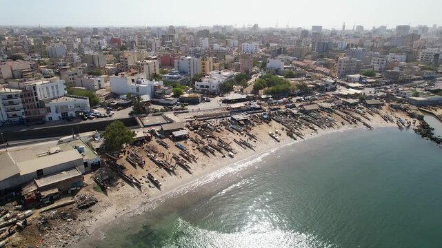 SENEGAL - 7.14.2025 - Wonderful aerial footage moving from the water to the boat-strewn beach and city buildings of Dakar, Senegal.