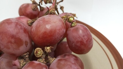 red grapes on a plate with a white background