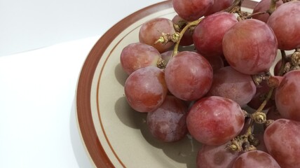 red grapes on a plate with a white background
