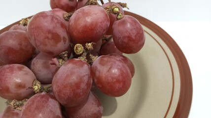 red grapes on a plate with a white background
