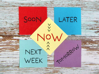 Stop procrastination concept with words of soon, later, tomorrow, next week and now on notepaper...