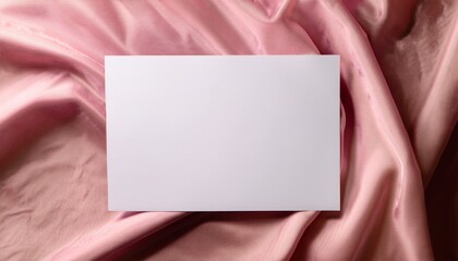Fototapeta premium blank white paper rectangle on a textured draped blush pink fabric