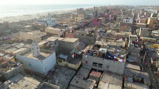 SENEGAL - 7.16.2025 - Amazing aerial footage moving across a beachside neighborhood as cars drive through on Senegal's Island of Saint-Louis.