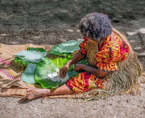 Local woman preparing laplap Manioc, with grated cassava, coconut milk, and salt, wrapped in banana...