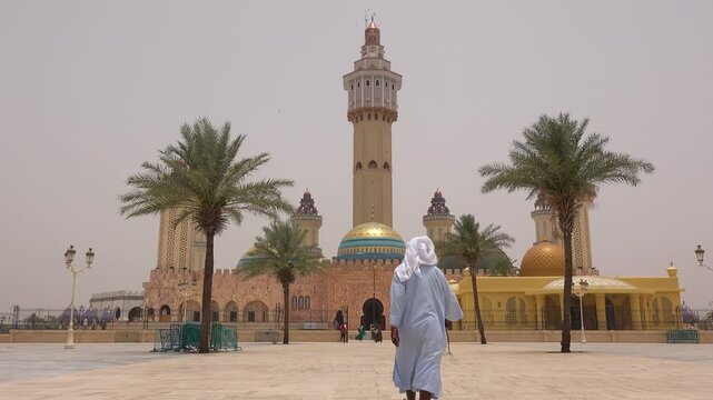 SENEGAL - 7.31.2025 - Ground level view of a man approaching the entrance to Senegal's Great Mosque Of Touba.