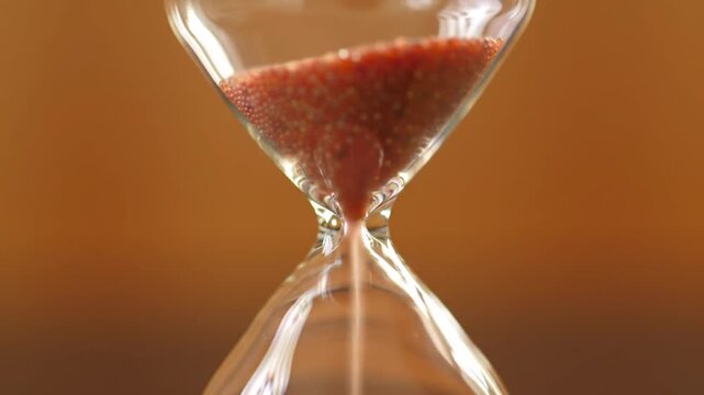 Hourglass with Red Sand Flowing, Time Passing Concept, Brown Background