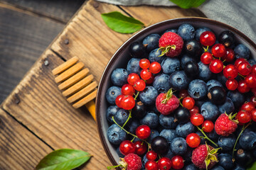 Freshly harvested berries in bowl on the rustic background. Summer berries. Shot from above.