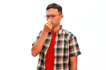 An Asian man holds his nose with an uncomfortable expression.
