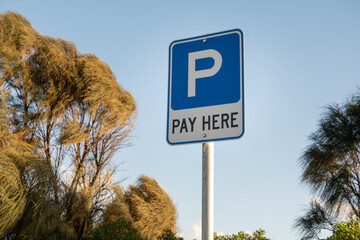 Parking sign with “Pay Here” instruction at a public car park, indicating a nearby ticket...