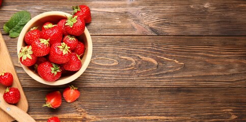 Bowl of sweet ripe strawberries on wooden background with space for text