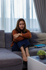 Asian woman feeling stress and headache on sofa. She used her hand to touch her face she has a...