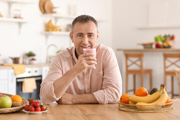 Mature man drinking fresh fruit smoothie in kitchen