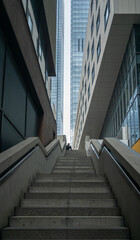 Person Sitting at Top of Urban Stairway Between Modern Skyscrapers