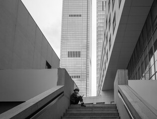 Black and White Urban Scene with Person Reading on Stairway