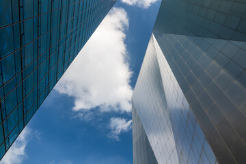 Modern Glass Skyscrapers Against Blue Sky with White Clouds