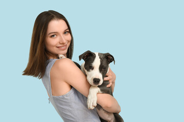 Beautiful young woman with cute staffordshire terrier puppy on blue background