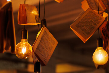 Many books floating in the air, along with light bulbs and warm lighting