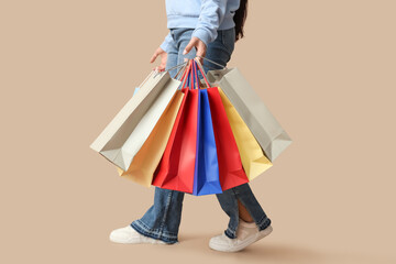 Young woman with many shopping bags on brown background
