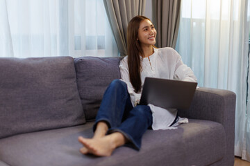 Fototapeta premium Asian woman using on laptop on sofa at home 