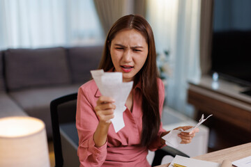 Asian woman work on laptop at home pay bills taxes on gadget online household budget on computer. 

